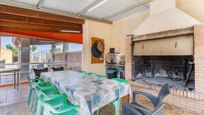 A dining area with a brick fireplace, green plastic chairs, and a table with a patterned tablecloth. - Country House 'La Romana' with Private Pool, Wi-Fi and Air Conditioning (La Romana)