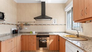 A kitchen with wooden cabinets, a stainless steel range hood, a built-in oven, a dishwasher, and a window with a view. - Country House 'La Romana' with Private Pool, Wi-Fi and Air Conditioning (La Romana)