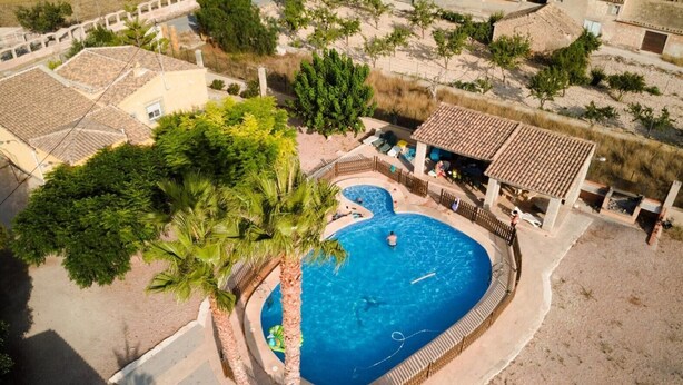 An aerial view of a resort with a swimming pool surrounded by palm trees and a fenced area. - Country House 'La Romana' with Private Pool, Wi-Fi and Air Conditioning (La Romana)