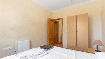 Een slaapkamer met een bed, een kast, een radiator en een lamp.