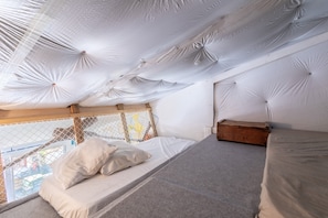 A bedroom with a bunk bed, a window with a view, and a ceiling with a unique design. - Studio Apartment 'Repaire Des Pirates Sainte Marie' with Private Terrace, Wi-Fi and Air Conditioning (Sainte-Marie-la-Mer)
