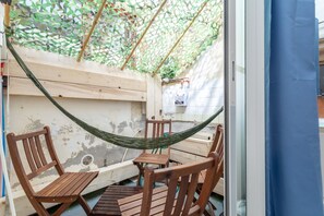 A hammock chair set up in a wooden outdoor space with a white wall and a green netted structure overhead. - Studio Apartment 'Repaire Des Pirates Sainte Marie' with Private Terrace, Wi-Fi and Air Conditioning (Sainte-Marie-la-Mer)