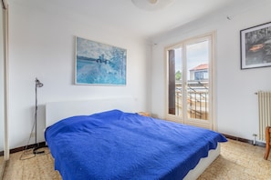 Une chambre à coucher avec un lit, une fenêtre, un radiateur et un tableau accroché au mur.