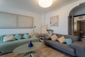 Un salon avec deux canapés, une table basse, une maquette de voilier et une horloge au mur.