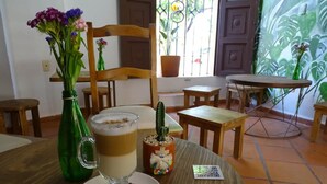Une table à manger avec une boisson chaude, une bouteille verte et une plante succulente.