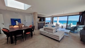 Ein modernes Wohnzimmer mit Essbereich, großen Fenstern und Meerblick.