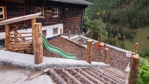 Une cabane en bois avec un toboggan, située sur une colline boisée.