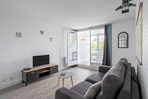 Una sala de estar moderna con un sofá, televisor y una pequeña mesa.
