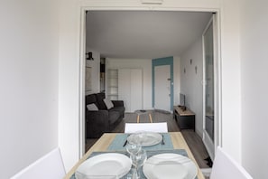 A dining area with a table set for four, a sofa, and a TV in the background.