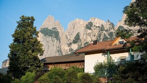 Una casa de montaña con balcón, rodeada de árboles y con vista a la montaña.