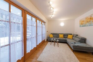 A living room with a grey sofa, yellow cushions, a small table with cups, and a white rug.