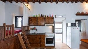 A kitchen with wooden cabinets, a stove, a microwave, and a refrigerator. - Holiday Home '1900's Traditional House in Asklipio' with Private Terrace, Wi-Fi and Air Conditioning (Rhodes)