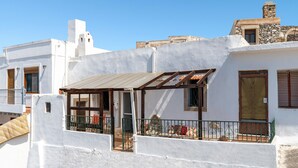 A white building with a balcony, a stone chimney, and a metal roof. - Holiday Home '1900's Traditional House in Asklipio' with Private Terrace, Wi-Fi and Air Conditioning (Rhodes)