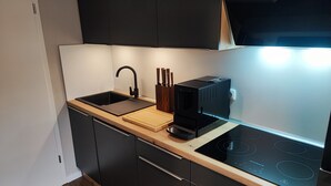 Una cocina moderna con encimera negra, un fregadero, una tabla de cortar y un horno empotrado.