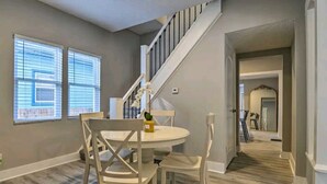 A dining area with a round table and four chairs, a staircase, and a hallway leading to another room. - 5 Mins From Fountain Square ! (Indianapolis)