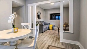 A modern living room with a grey sofa, a round table with chairs, a small plant, and a mirror on the wall. - 5 Mins From Fountain Square ! (Indianapolis)