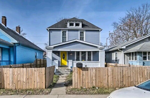 A two-story house with a front porch, a visible front door, and a wooden fence. - 5 Mins From Fountain Square ! (Indianapolis)
