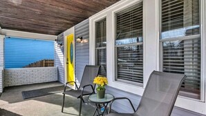 A covered porch with two chairs, a small table with a potted plant, and a blue garage door. - 5 Mins From Fountain Square ! (Indianapolis)