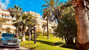 A hotel with a lush garden, palm trees, and a parked car. - StudioCalifornia-Parking-Plages 15 min walk (CANNES)