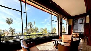 A spacious room with large windows offering a view of palm trees and a clear sky. - StudioCalifornia-Parking-Plages 15 min walk (CANNES)
