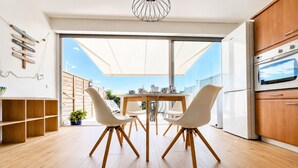 A modern kitchen with wooden cabinets, a built-in oven, and a dining area with a table and chairs.