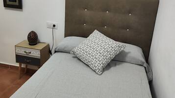 Un dormitorio con cama, una mesita de noche, una lámpara y dos cuadros en la pared.