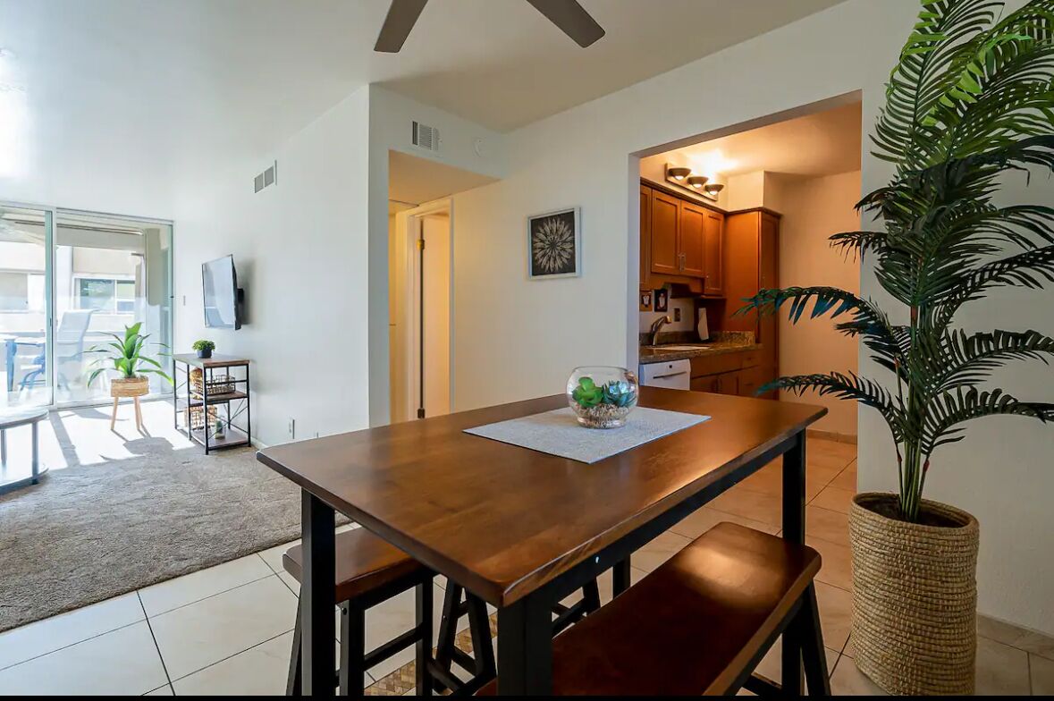 A dining area with a wooden table, benches, and a potted plant.