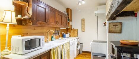 A compact kitchen with wooden cabinets, a microwave, a washing machine, and a small sink.