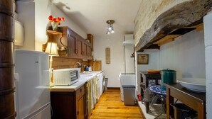 Une cuisine étroite avec des meubles en bois, un four à micro-ondes, un lave-linge et un coin repas comprenant une table et des chaises.