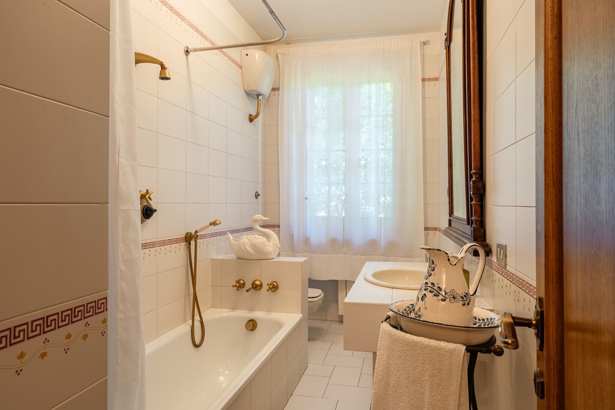 Un baño con bañera, lavamanos, espejo y ducha.