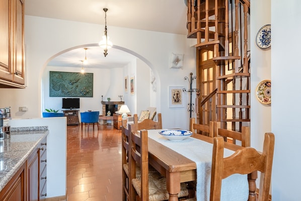Eine geräumige Küche mit Essbereich, einer Holztreppe und einem Fernseher im Hintergrund.