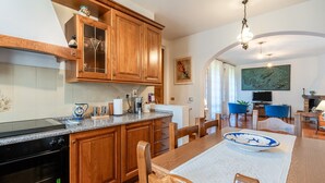 Una cocina con armarios de madera, un horno negro y un comedor con mesa y sillas.