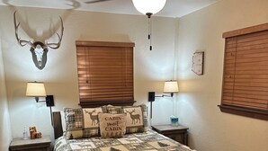 Un dormitorio con una cama de madera, un ventilador de techo y una decoración de cabeza de ciervo en la pared.