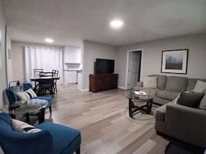 Ein Wohnzimmer mit Essbereich, Fernseher und einer Couch.