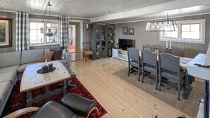 Un grand espace de vie comprenant un canapé, une table à manger et des chaises, un téléviseur et une cheminée.