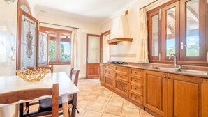 Une cuisine avec des meubles de rangement en bois, une table à manger et une fenêtre avec des rideaux.