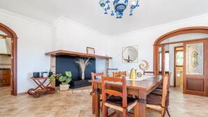 Un coin repas avec une table et des chaises en bois, une cheminée et un lustre.