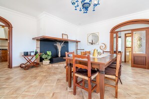 A dining area with a wooden table and chairs, a fireplace, and a chandelier. - Villa 'Finca Son Manxo' with Mountain View, Wi-Fi and Air Conditioning (Illes Balears)