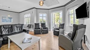 A spacious living room with a leather sofa, two armchairs, a wicker chair, and a white coffee table. - 5 bedroom nice home in Nyborg (Nyborg)