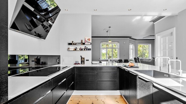 A modern kitchen with black cabinetry, a wooden floor, and a large window providing natural light. - 5 bedroom nice home in Nyborg (Nyborg)