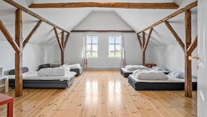 A room with a sloped ceiling, wooden beams, two windows, and two beds. - 5 bedroom nice home in Nyborg (Nyborg)