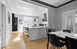 Enjoy meals in the kitchen with a central island and oven, adjacent to a dining area with a table and chairs.