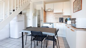 Une cuisine avec des meubles blancs, une table à manger avec des chaises, un four à micro-ondes et un grille-pain.