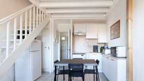 Une cuisine équipée d’une table et de chaises, d’un réfrigérateur, de placards et d’un escalier.