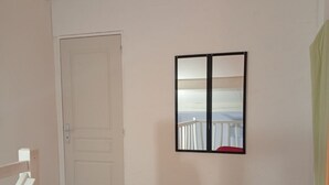 Une pièce avec une porte fermée, un tableau encadré au mur et un tapis rouge sur le sol.