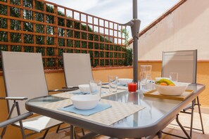 Mesa al aire libre con sillas, una superficie de cristal y un frutero.