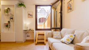 A living room with a sofa, a wooden ladder, a window with a view of a building, and a white cabinet with shelves. - Apartment 'Sauc Beach' with Private Terrace, Wi-Fi and Air Conditioning (Canet de Mar)