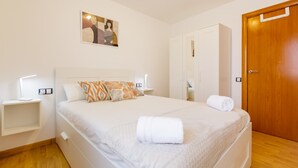 A bedroom with a bed, bedside tables, a wardrobe, and a door. - Apartment 'Sauc Beach' with Private Terrace, Wi-Fi and Air Conditioning (Canet de Mar)
