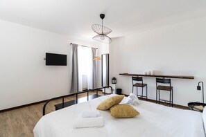Une chambre d’hôtel équipée d’un lit, d’une télévision, d’un bureau avec des chaises et d’un porte-manteau mural.