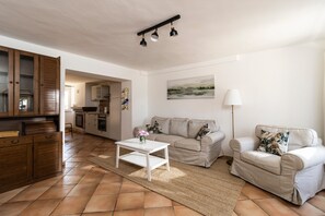 Una sala de estar con sofá, sillón, mesa de centro y un cuadro en la pared.